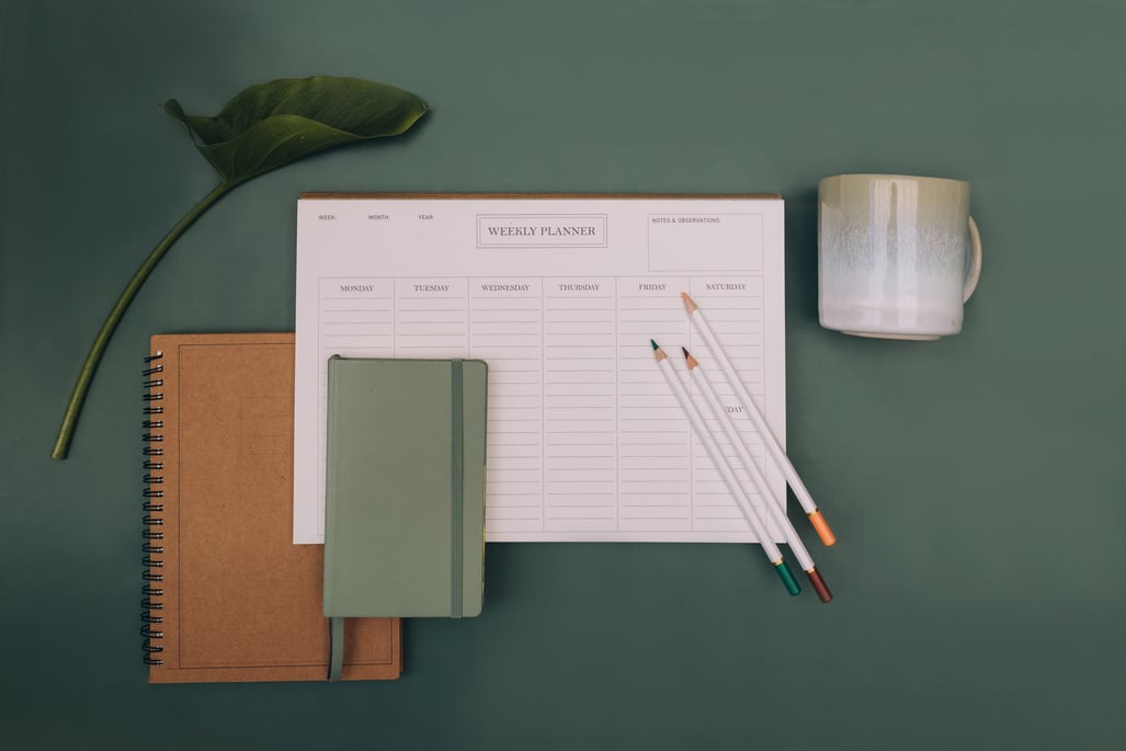 Notebooks, Calendar, Mug and Pencils on Green Background